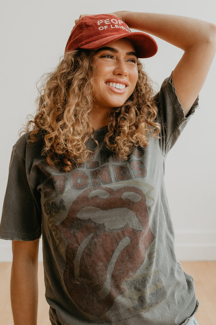 Person wearing a Rolling Stones t-shirt and a red cap with text, standing against a plain background