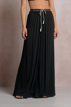 Black flowing skirt with a white drawstring on a neutral background
