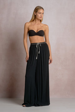 Woman wearing a black strapless top and long black skirt against a neutral background