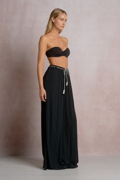 Woman wearing a black strapless top and long black skirt against a neutral background