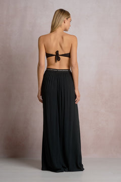 Woman wearing a black halter neck dress with a bow detail on a neutral background