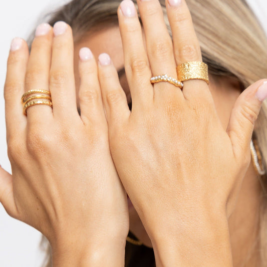 A women wearing 3 different style gold rings