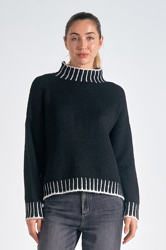 Person wearing a black sweater with white trim on a white background
