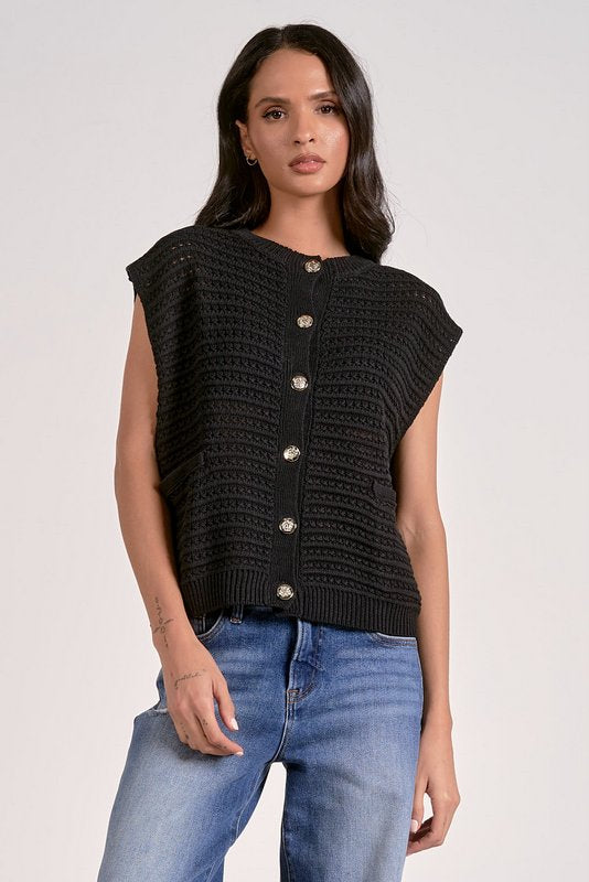 Woman wearing a black knitted vest with silver buttons on a white background