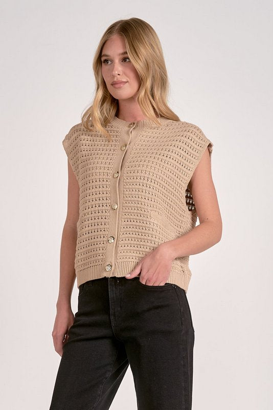 Woman wearing a beige crochet vest against a white background