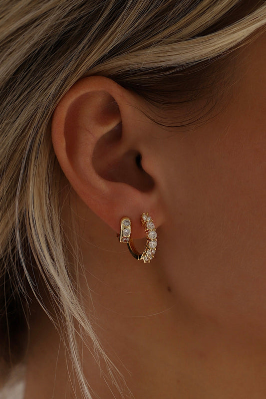 Close-up of an ear wearing gold hoop earrings with a blurred background