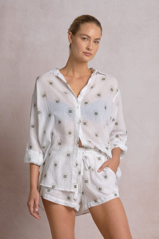 Woman wearing a white outfit with floral patterns on a plain background