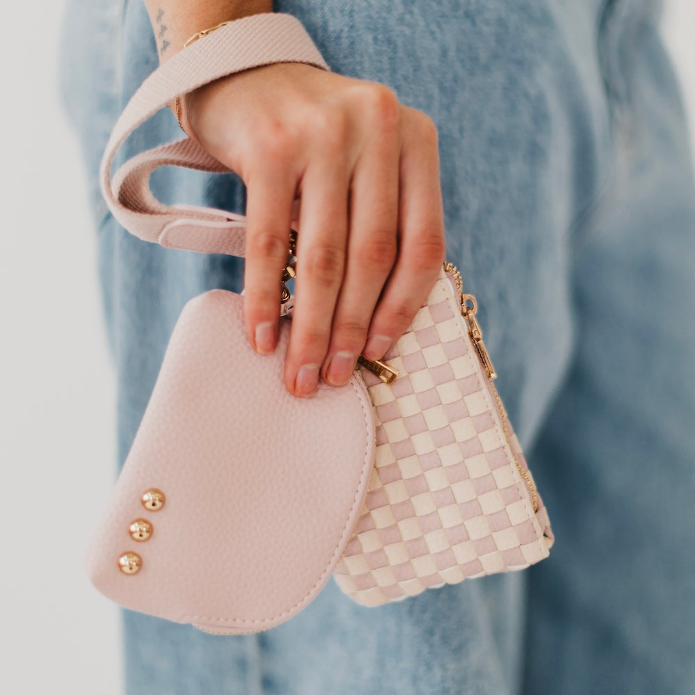 Hand holding two small pink handbags with a blurred blue background