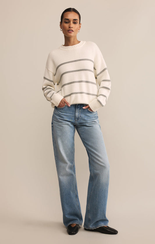 Woman wearing a striped sweater and jeans on a beige background