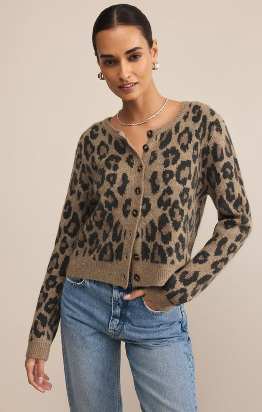 Woman wearing a leopard print cardigan and blue jeans on a beige background