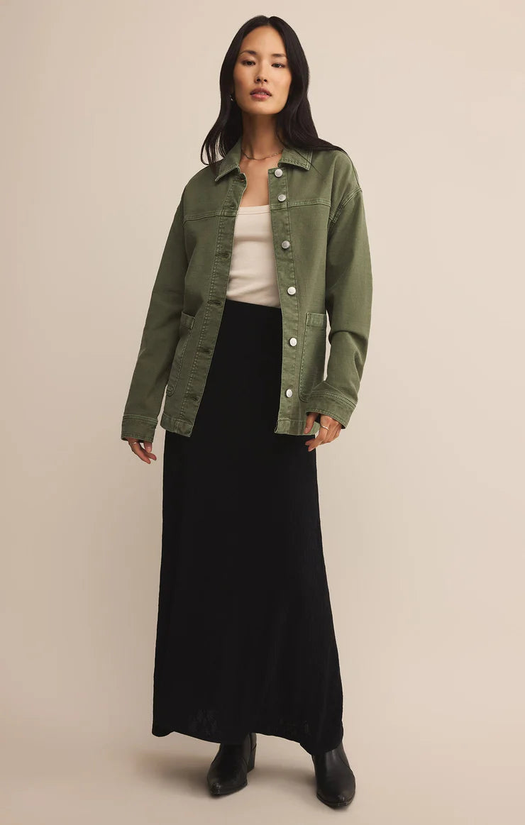 Women wearing long black skirt and olive green button down jacket with white tank