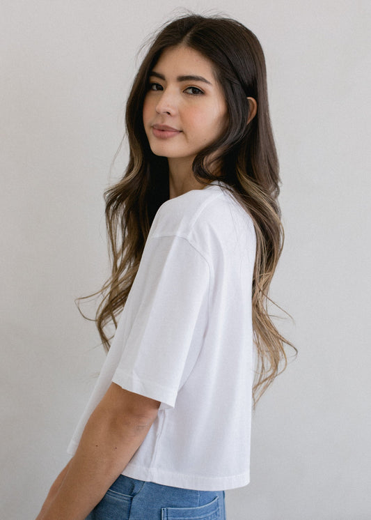 Woman wearing a white t-shirt and blue jeans against a plain background