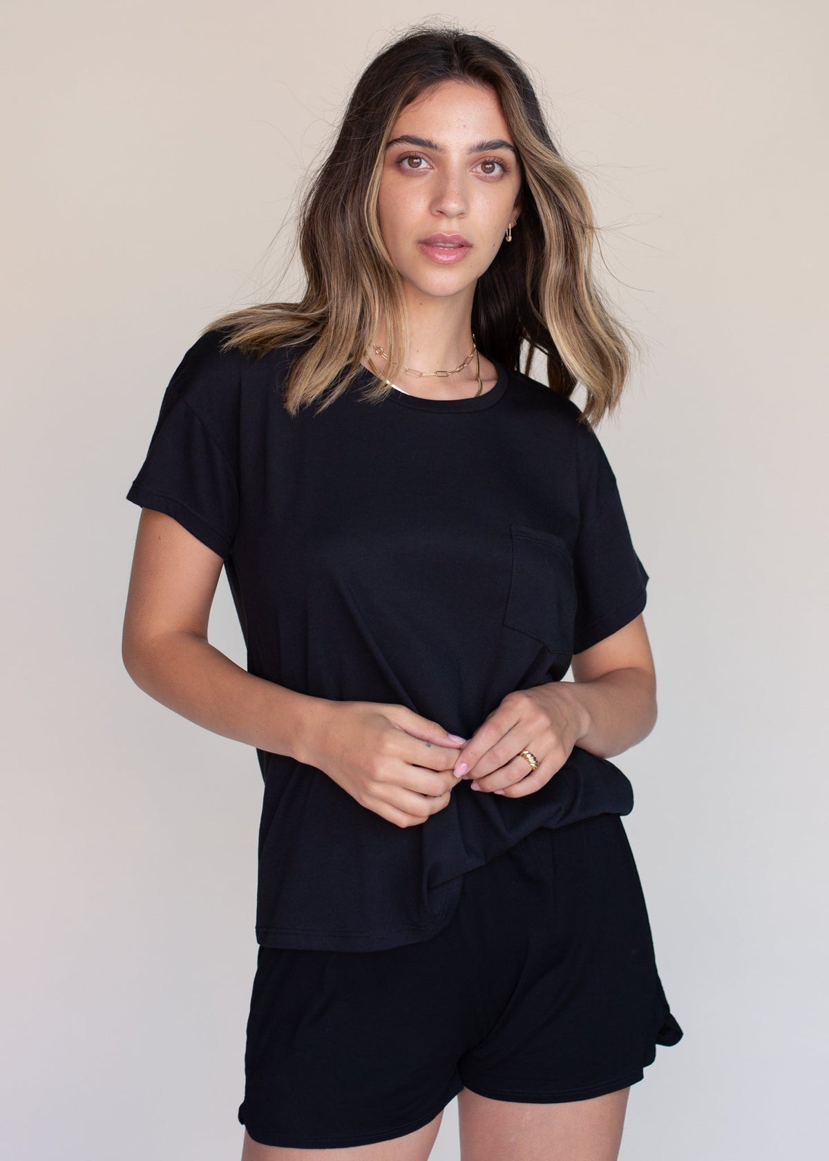 Woman wearing a black t-shirt and shorts against a plain background