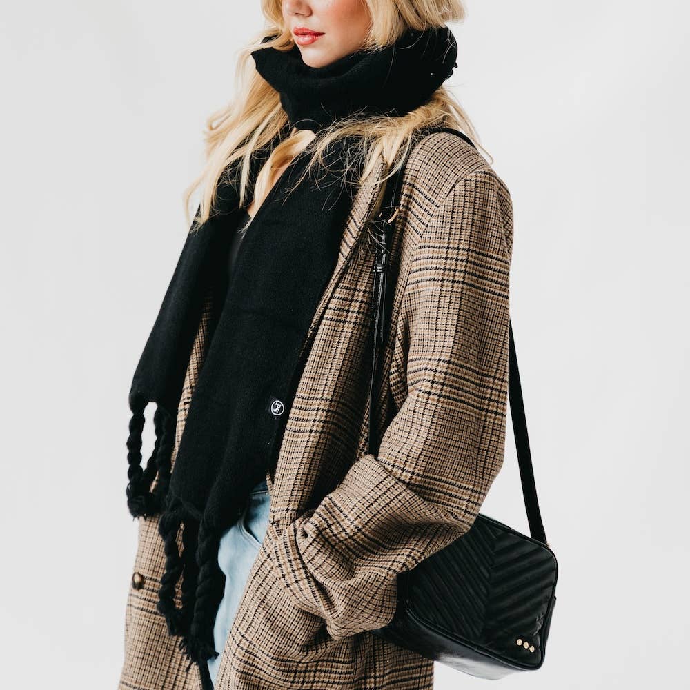 Person wearing a plaid coat and black scarf with a black handbag on a white background