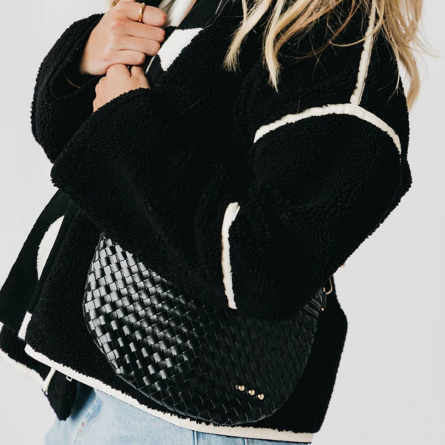 Black backpack with white accents held by a person on a light gray background