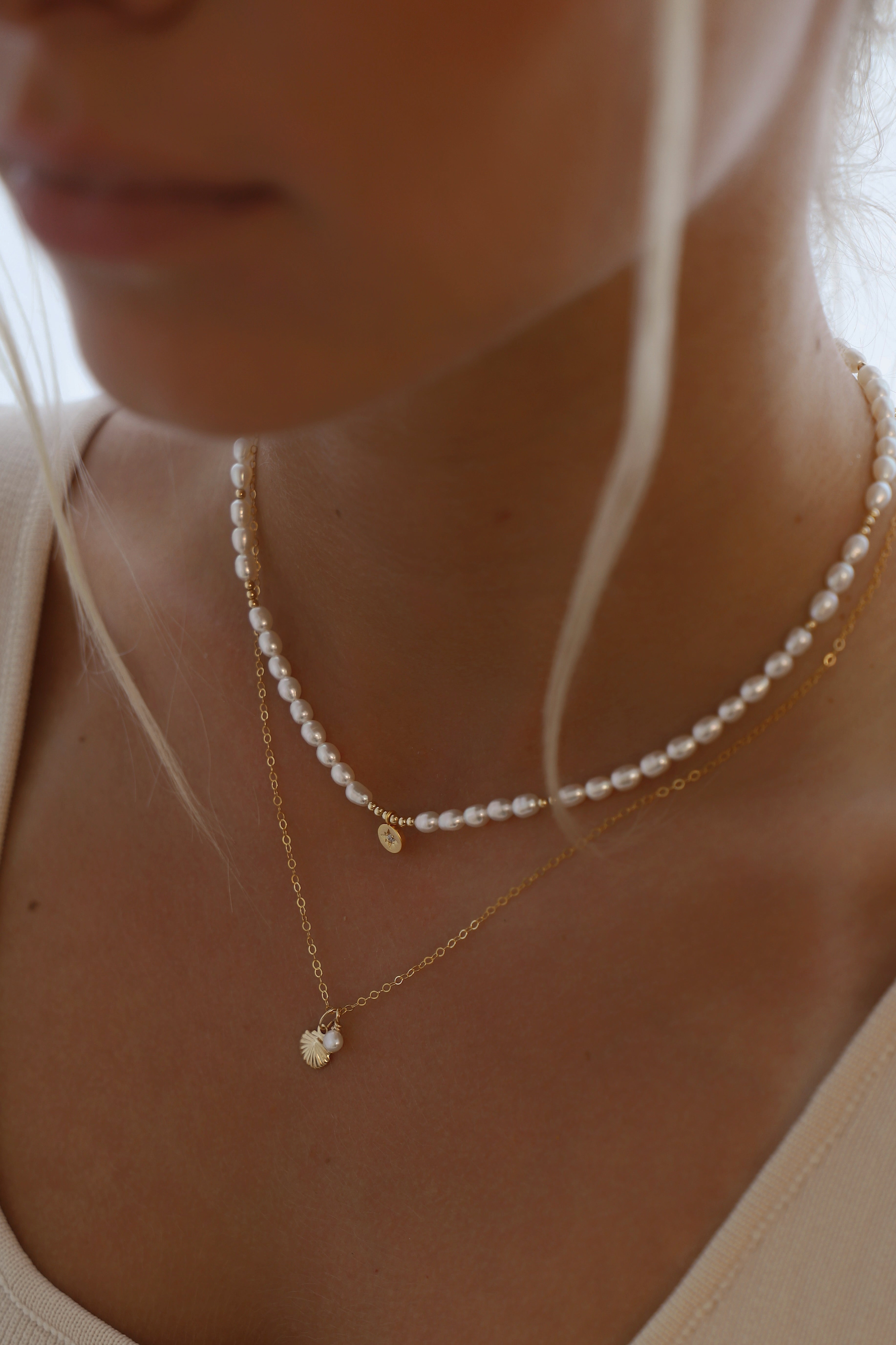 Close-up of a person wearing two pearl necklaces with a blurred background