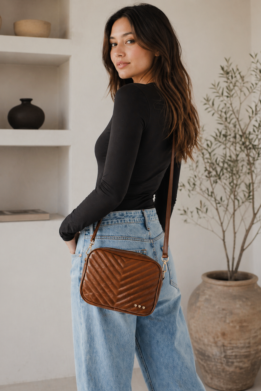 A woman in black long sleeve shirt and jeans with the quilted coco bag in mocha sold at rosiekarma.com