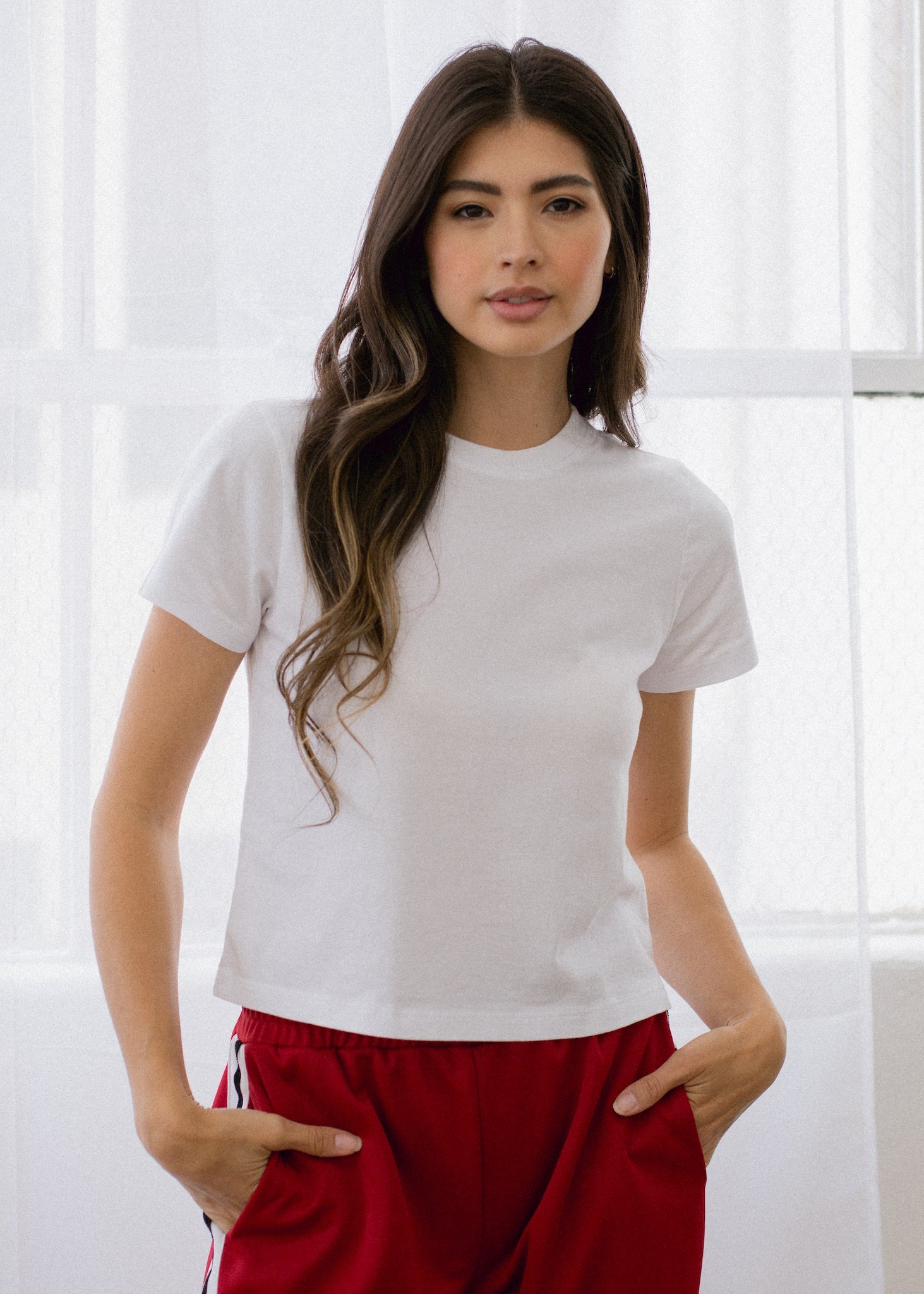 Woman wearing a white t-shirt and red pants against a white background
