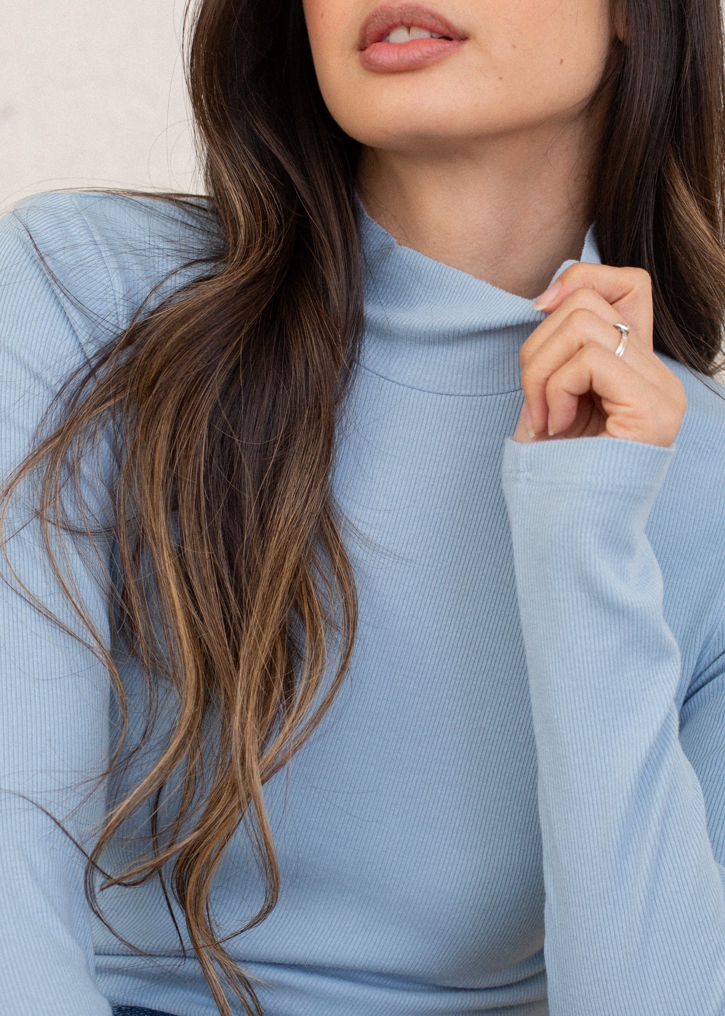 Close-up of a person wearing a light blue sweater with a neutral background