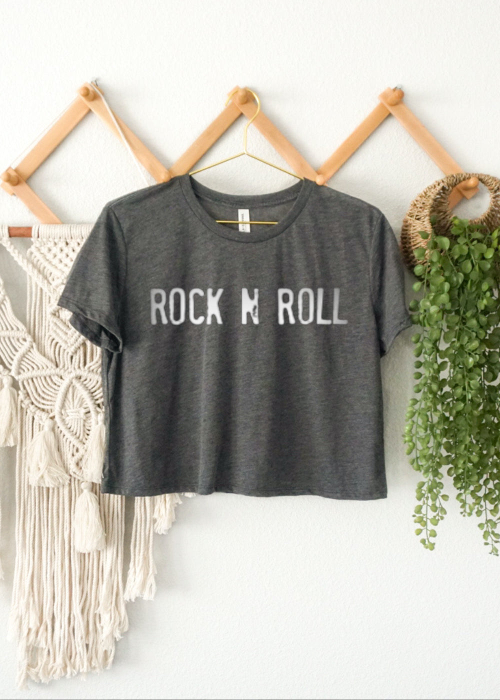 Gray t-shirt with 'Rock N Roll' text hanging on a rack with decorative elements.