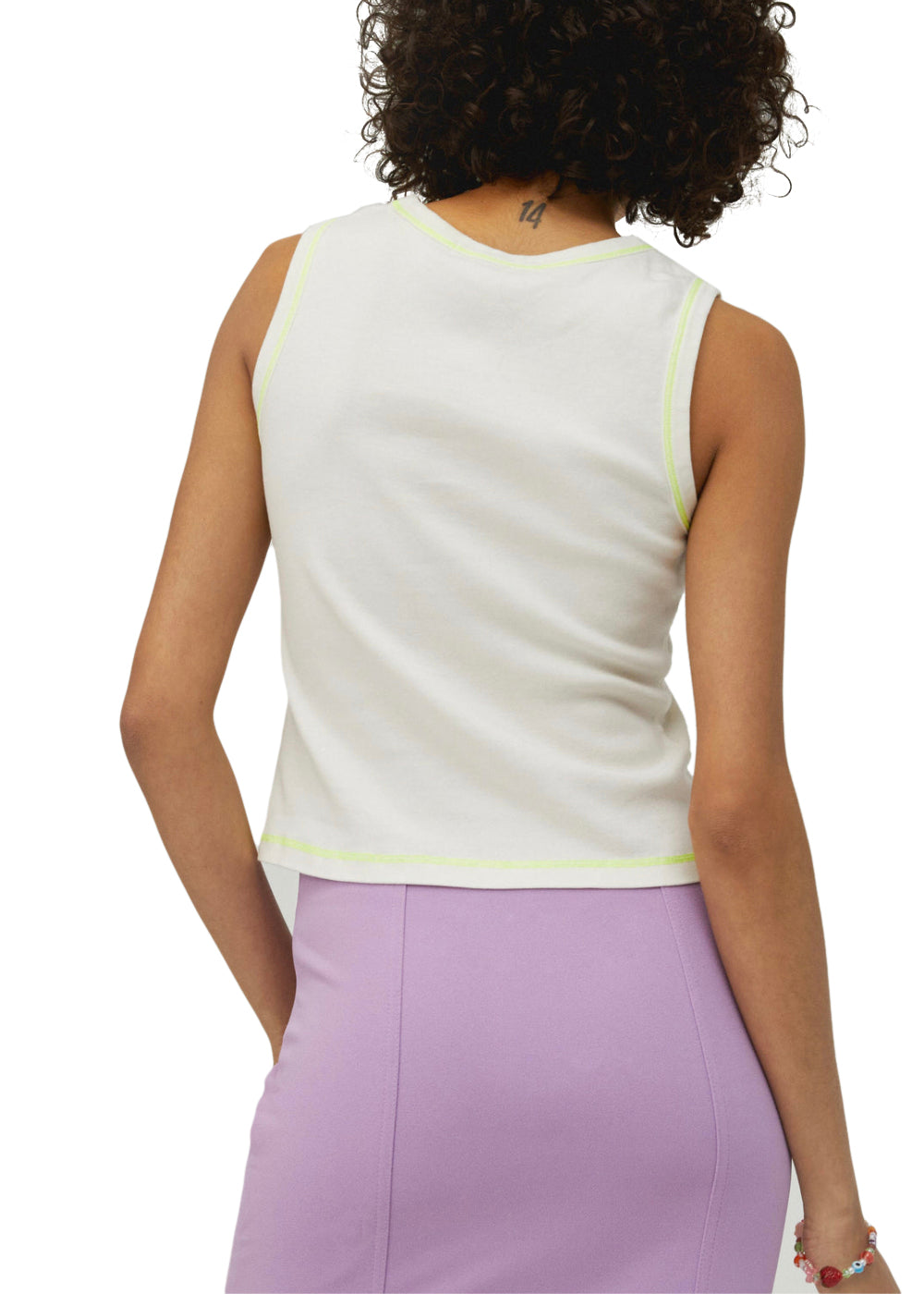 Woman wearing a white sleeveless top with yellow trim and a purple skirt on a white background