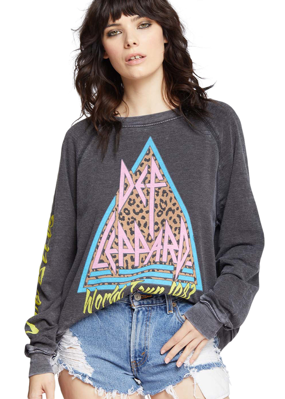 Woman wearing a dark gray sweatshirt with a colorful graphic design and denim shorts on a white background
