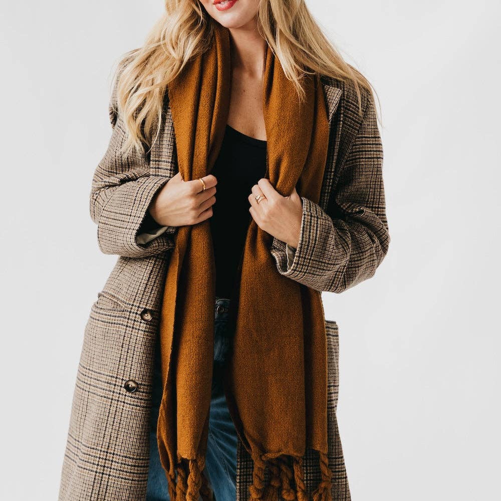 Woman wearing a plaid coat and brown scarf against a white background