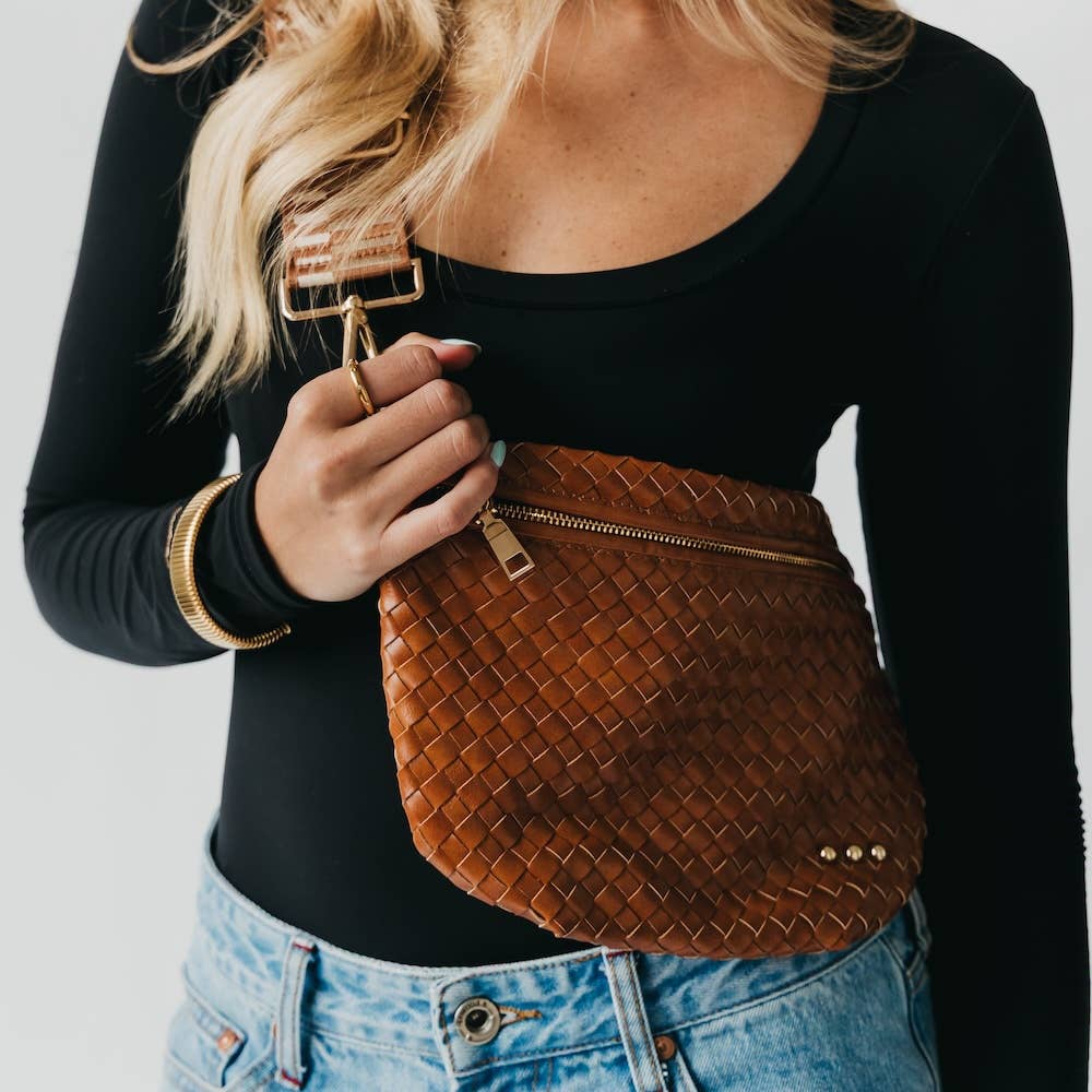 Person holding a brown woven handbag wearing a black bodysuit and jeans