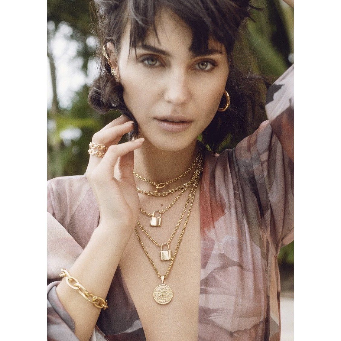 women wearing gold earrings, necklaces, rings and a bracelet