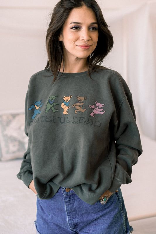 Person wearing a green sweatshirt with colorful bear illustrations and text.