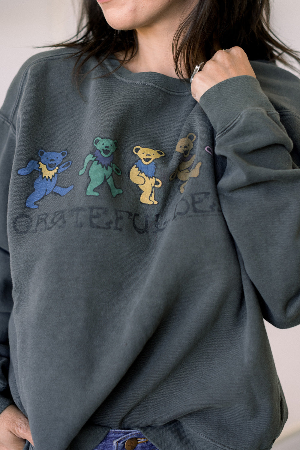 Person wearing a dark gray sweatshirt with embroidered bears and 'Grateful Dead' text.