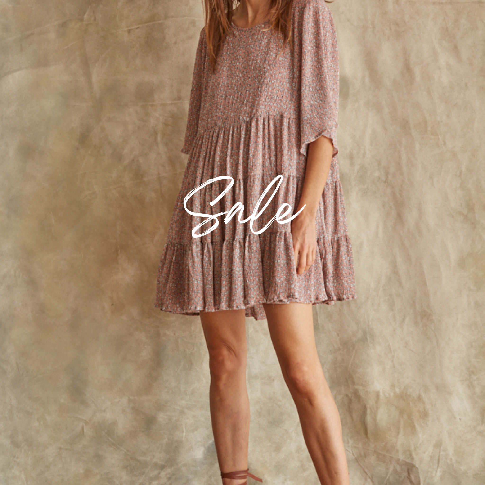 A woman wearing a short sleeve, knee-length brown chiffon dress with a round neckline and ruffle detailing.