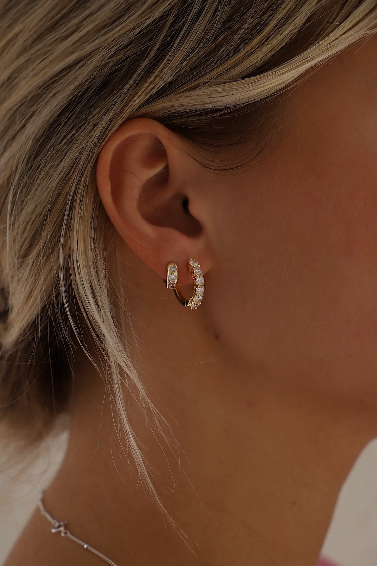 Close-up of a person wearing gold hoop earrings with a blurred background