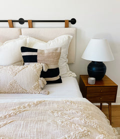 Decorative boho blanket layered on bed with neutral home decor