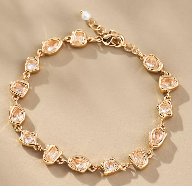 Gold bracelet with clear gemstones on a beige background