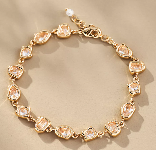 Gold bracelet with clear gemstones on a beige background