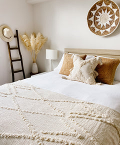 Decorative boho blanket layered on bed with neutral home decor