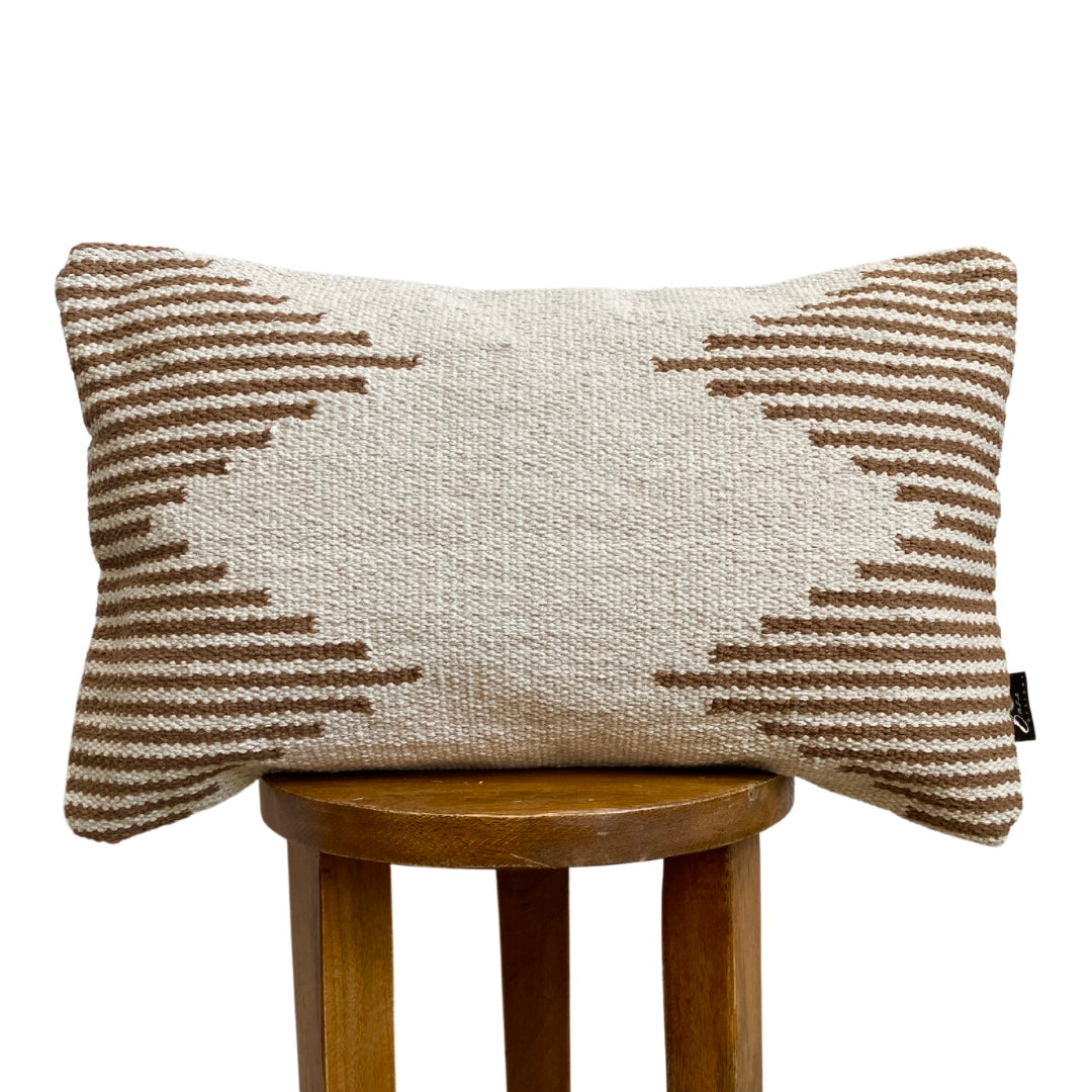 Textured pillow with geometric pattern on a wooden stool against a white background