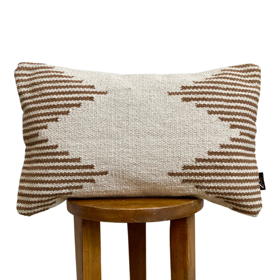 Textured pillow with geometric pattern on a wooden stool against a white background