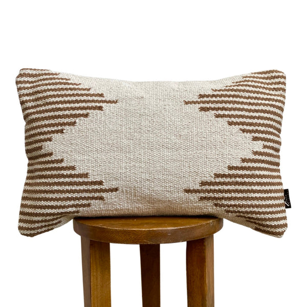 Textured pillow with geometric pattern on a wooden stool against a white background