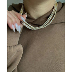 Close-up of a person wearing a brown garment with a sparkling necklace.