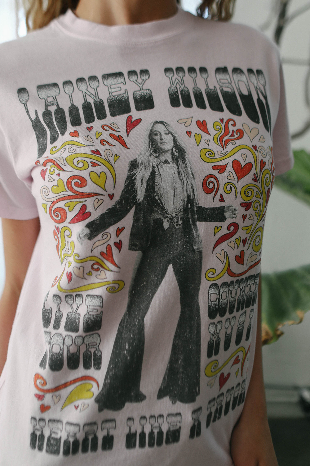 Person wearing a t-shirt with a graphic design of a person in a suit and colorful patterns.