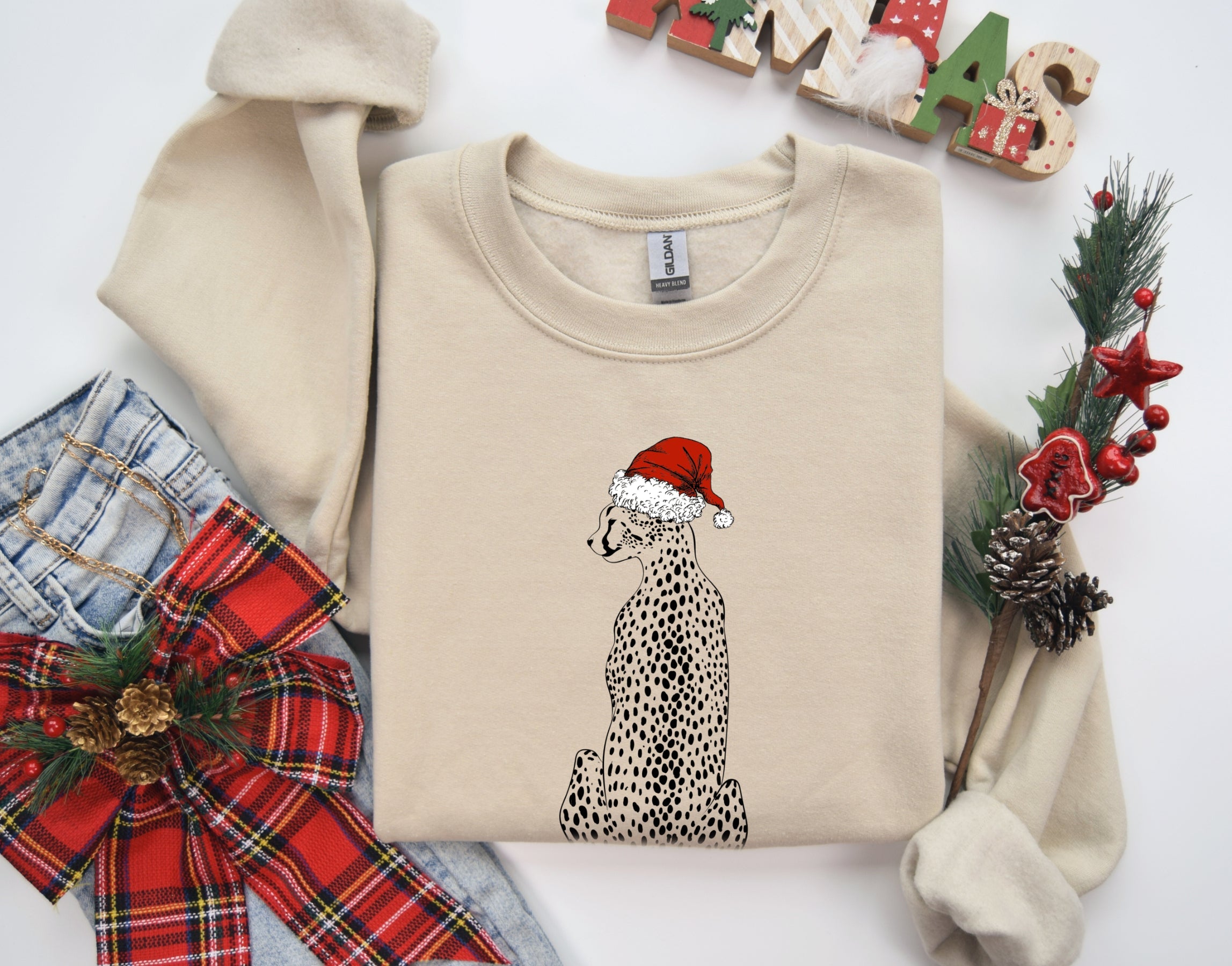Beige sweatshirt with a Christmas-themed design of a cheetah wearing a Santa hat, surrounded by festive decorations on a white background.