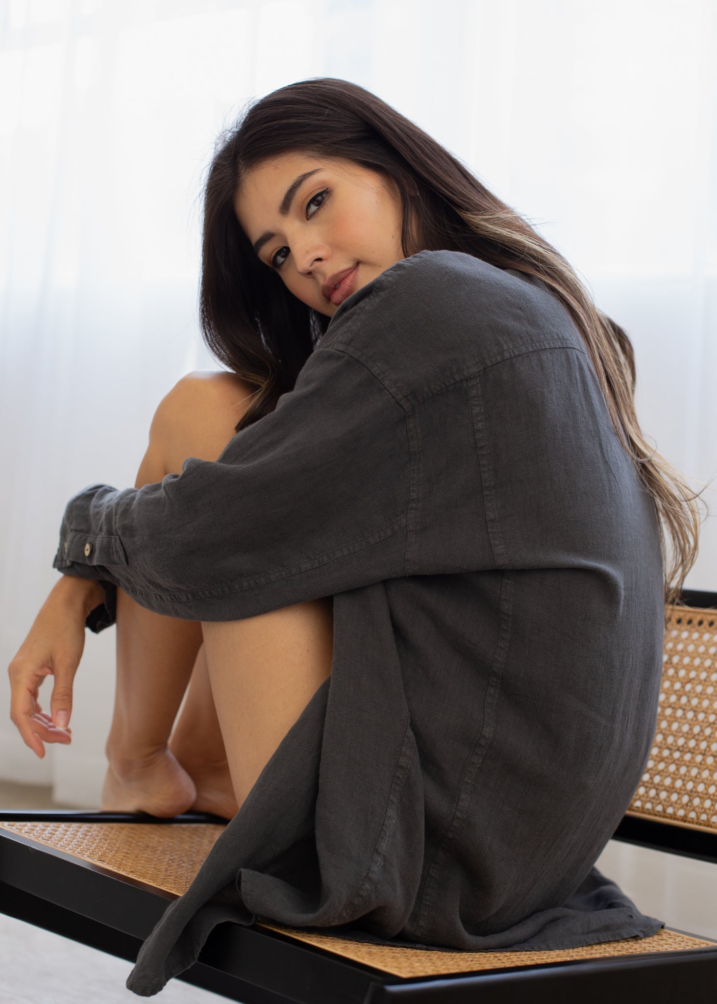 Woman sitting on a bench wearing an oversized dark shirt with a blurred background