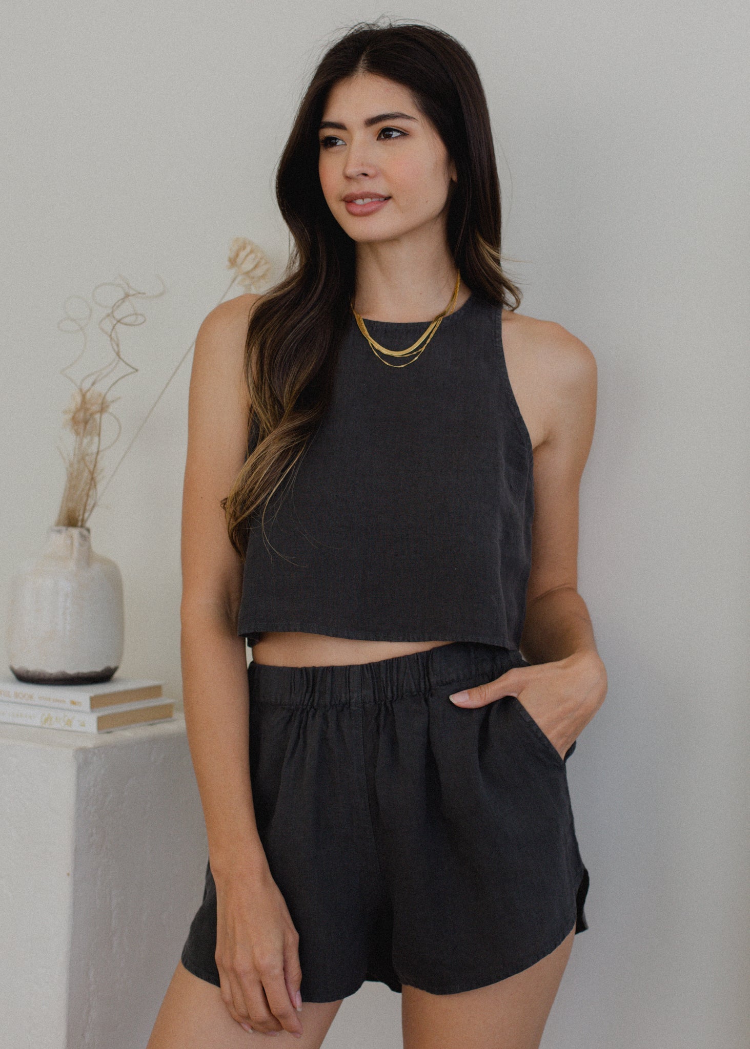 Woman wearing a black sleeveless top and shorts against a neutral background