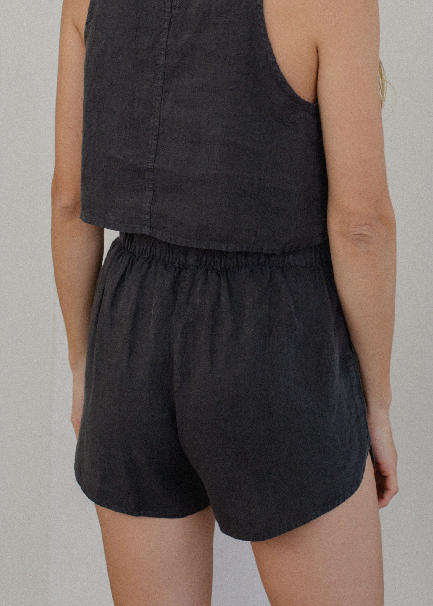 Person wearing a black sleeveless top and shorts on a plain background