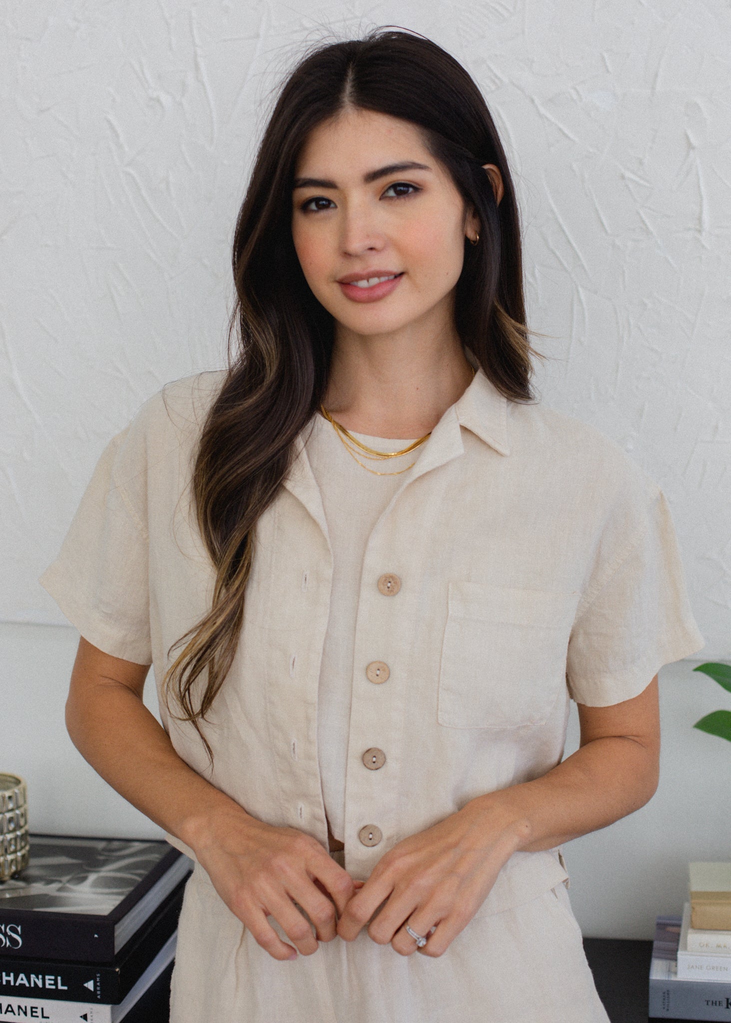 Woman wearing a beige shirt against a white wall