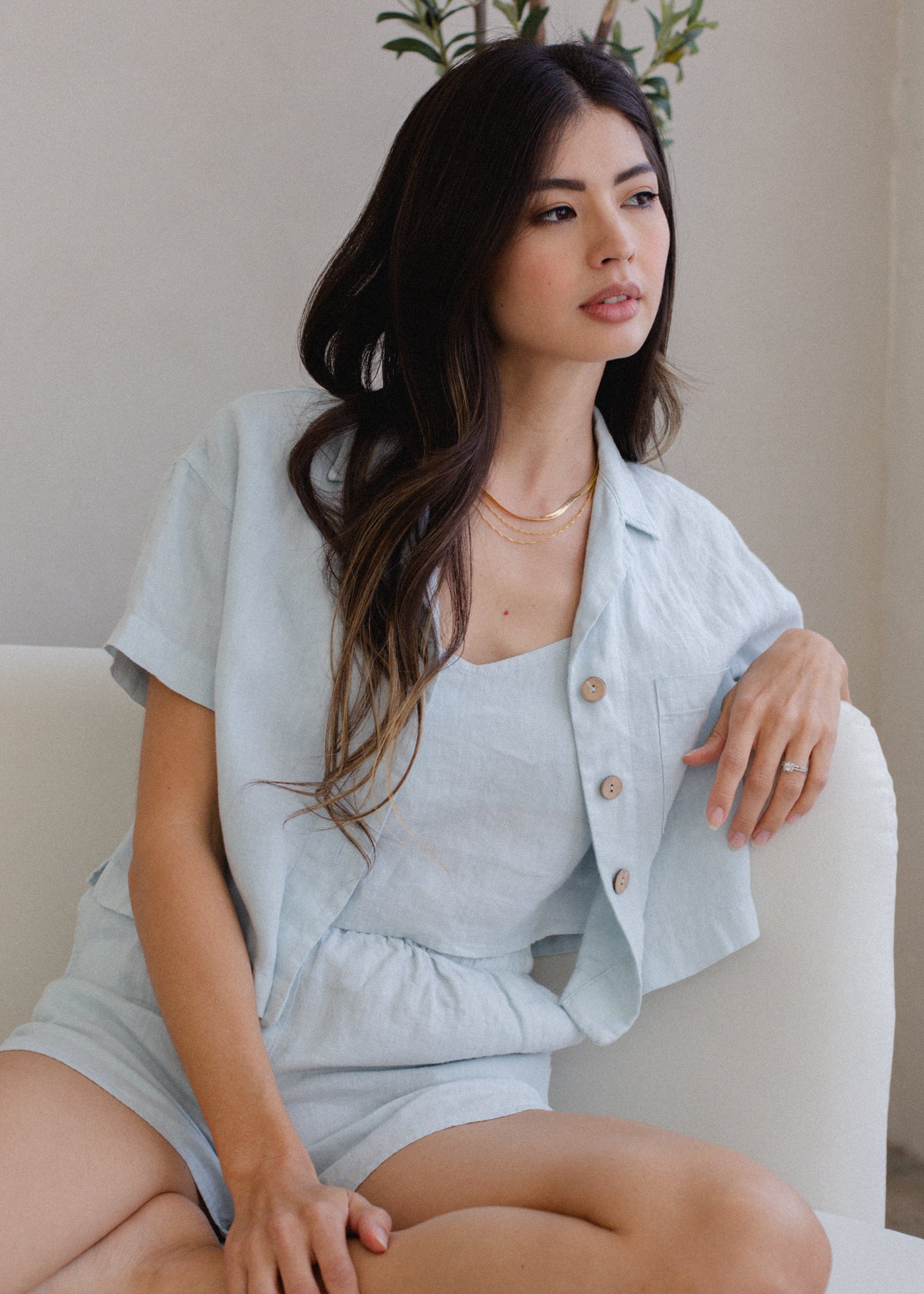 Woman wearing a light blue outfit sitting on a white couch.