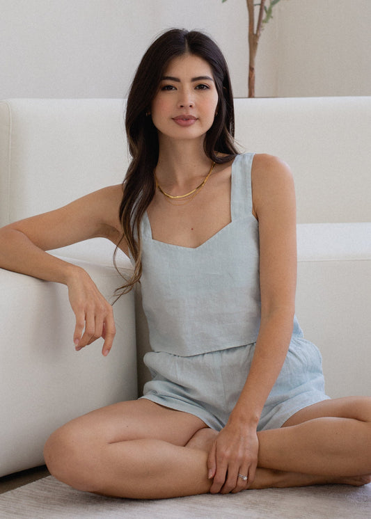 Woman sitting on a white couch wearing a light blue dress.