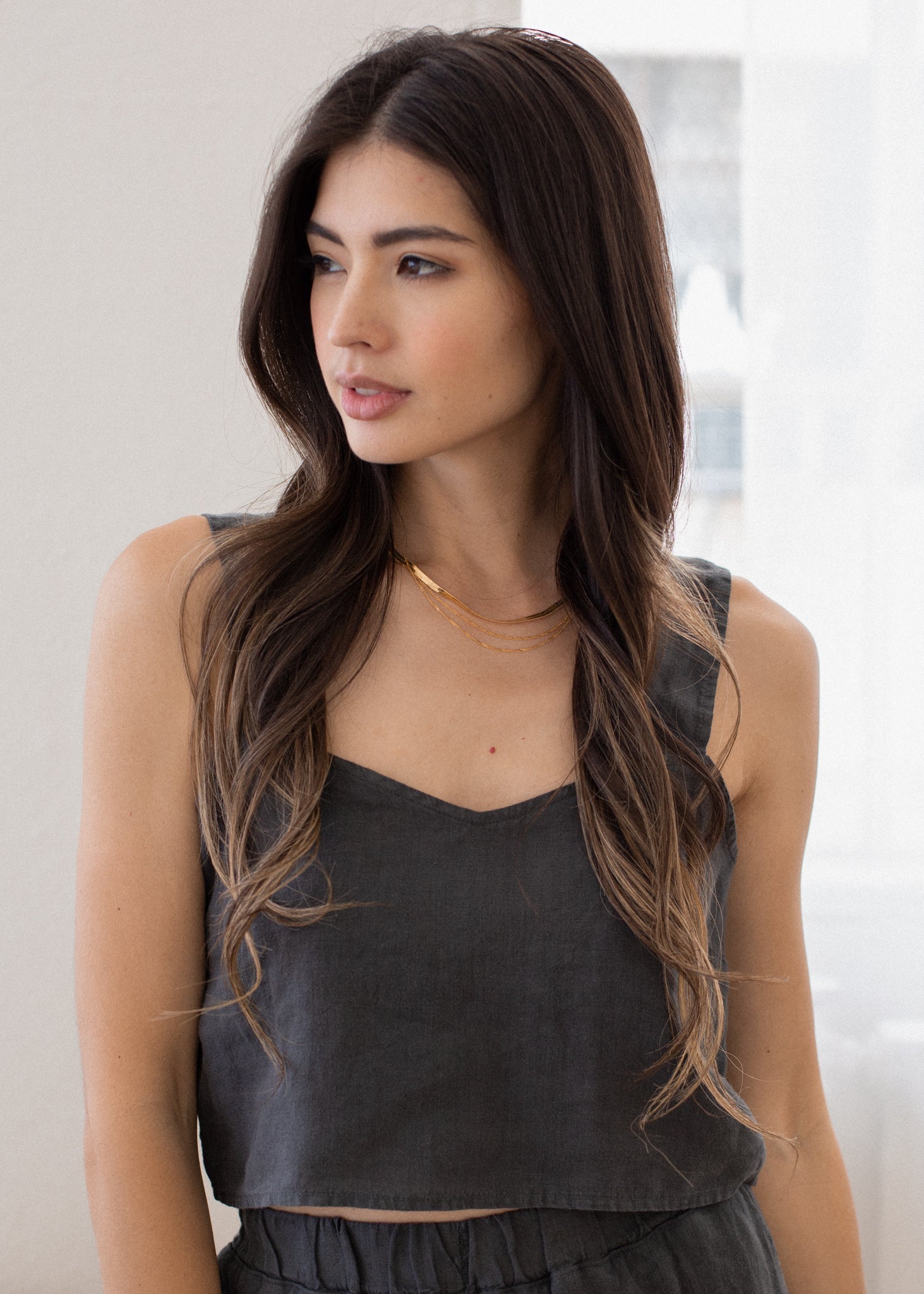 Woman wearing a dark gray tank top against a neutral background
